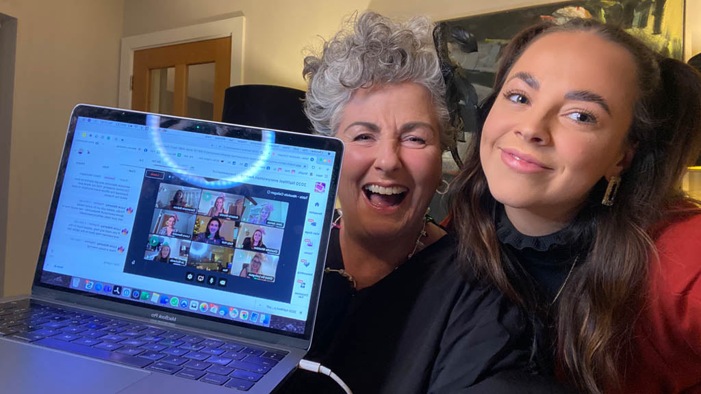 Foto von Maxine und Margot Laceby, die einen Computer hochhalten, mit Bildern von Team AC bei einer virtuellen Presiverleihung